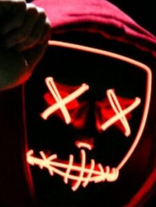 A spooky illuminated mask figure with a red hoodie in a dark setting, perfect for Halloween themes.